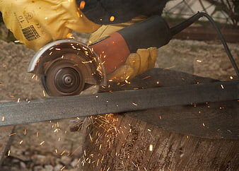 Close-up of hands using an angle grinder to cut metal with sparks