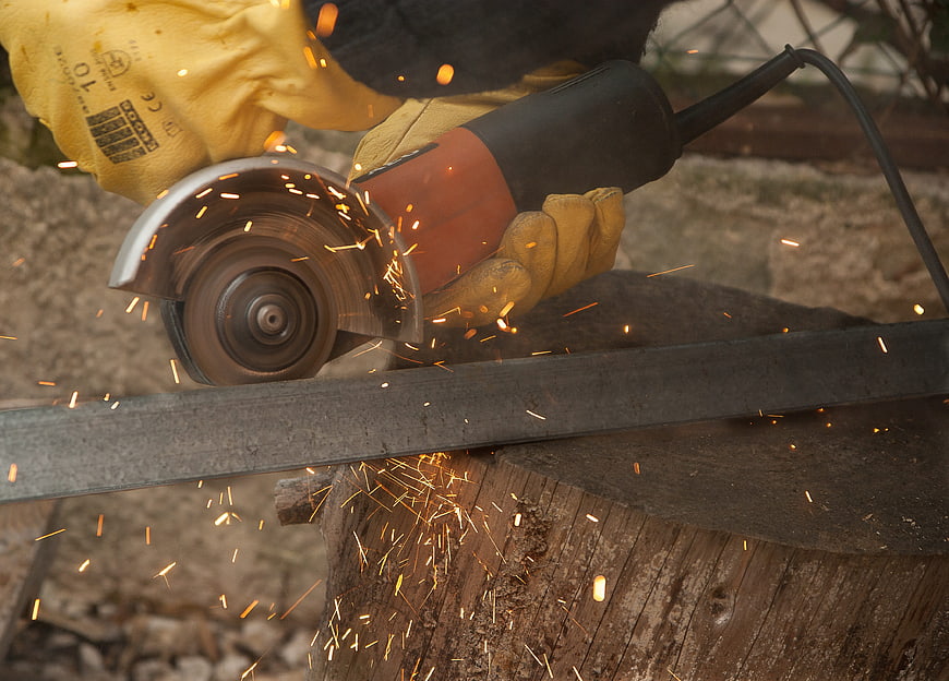 Close-up of hands using an angle grinder to cut metal with sparks