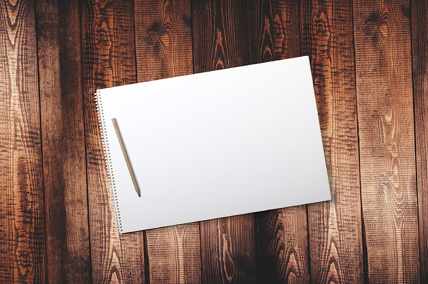 Blank spiral notebook and pencil on rustic wooden background