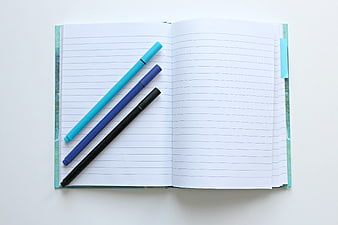 Open Notebook with Blue and Black Pens on White Background