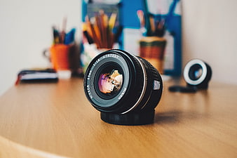 Nikon Camera Lens on Wooden Desk with Stationery