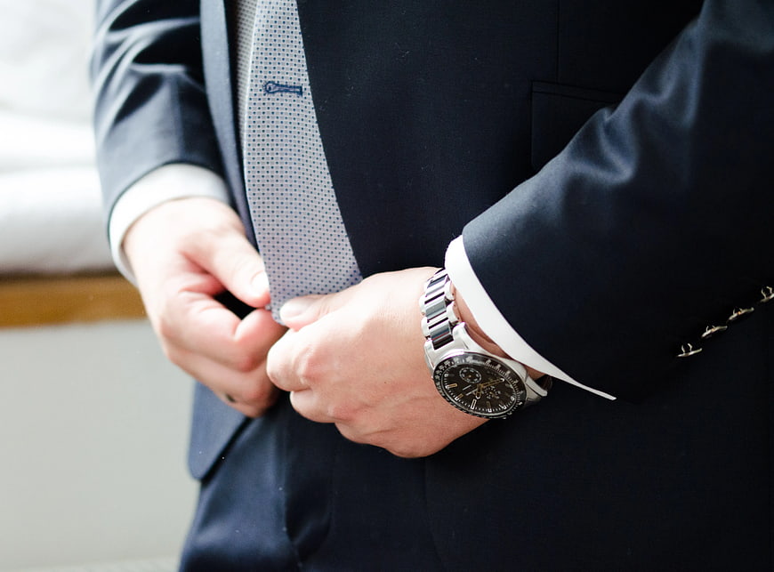Businessman adjusting suit jacket with luxury watch