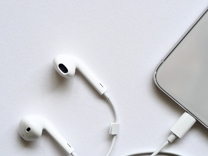 White wired earphones and smartphone on white background