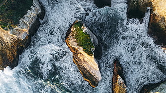 Aerial view of crashing ocean waves against rocky coastline