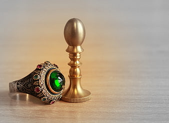 Vintage signet ring with green gemstone on wooden surface