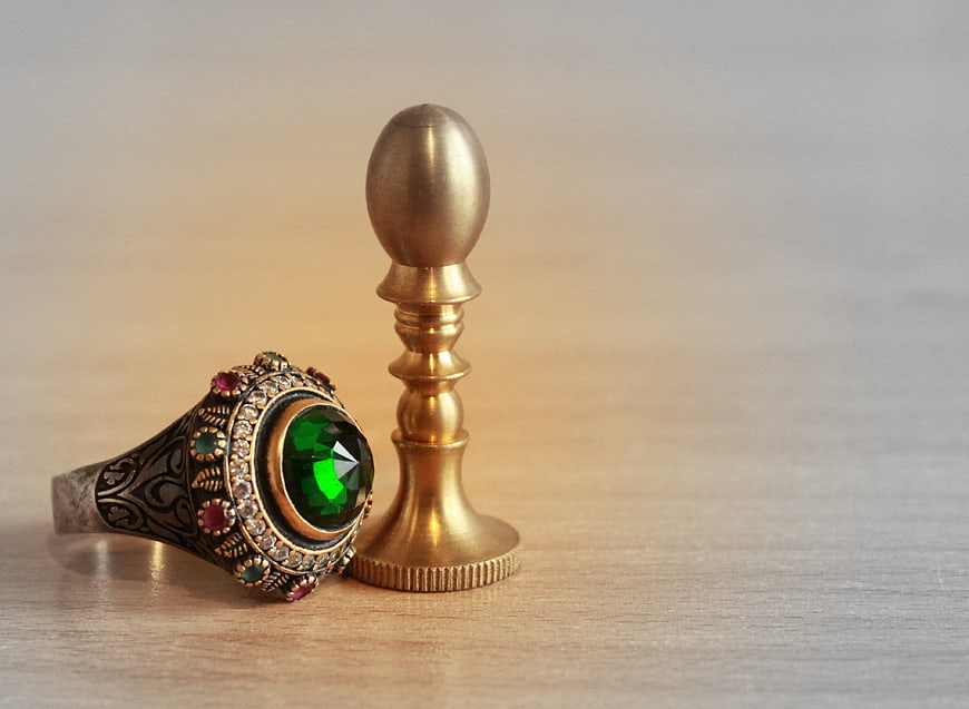 Vintage signet ring with green gemstone on wooden surface