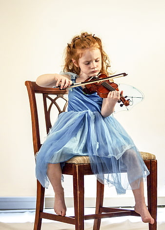 Young girl playing violin in blue dress