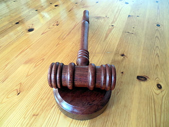 Wooden judge gavel and sound block on light pine table surface