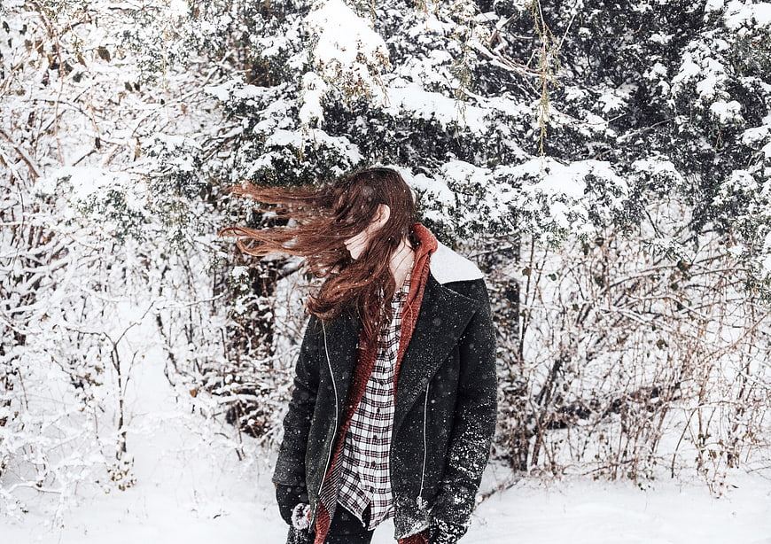 Woman with Windblown Hair in Snowy Winter Forest