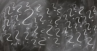 White chalk question marks on a dark blackboard background