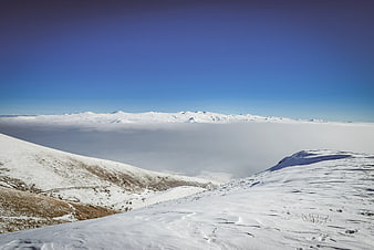 Snowy mountain peaks above sea of clouds winter landscape
