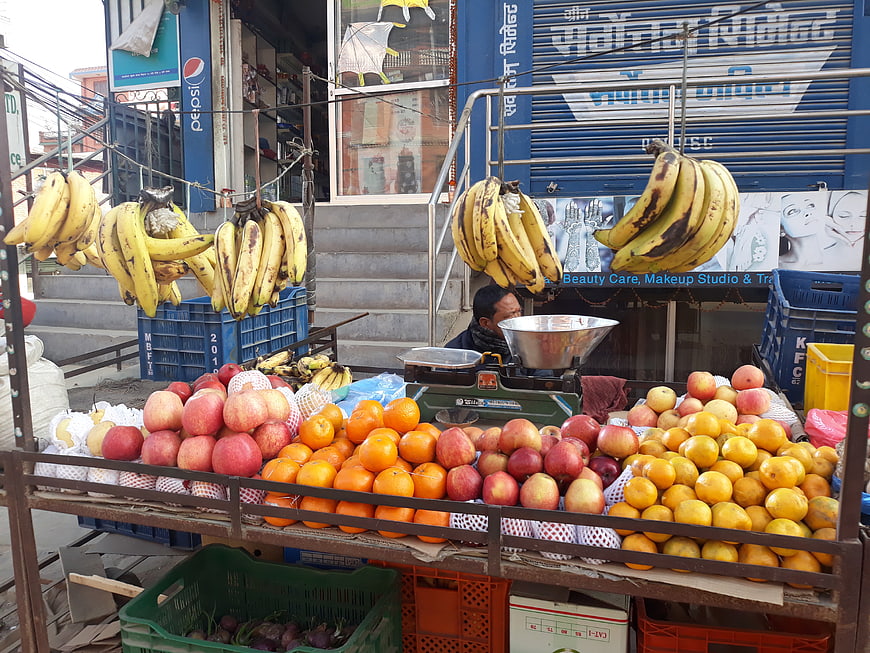 Street fruit vendor selling bananas, apples, and oranges in Nepal