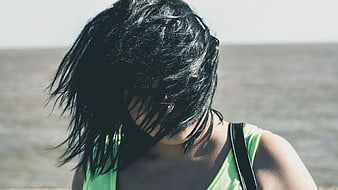 Woman with hair covering face by the ocean