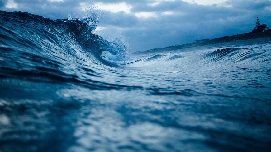 Dramatic Blue Ocean Wave Crashing Near Shoreline