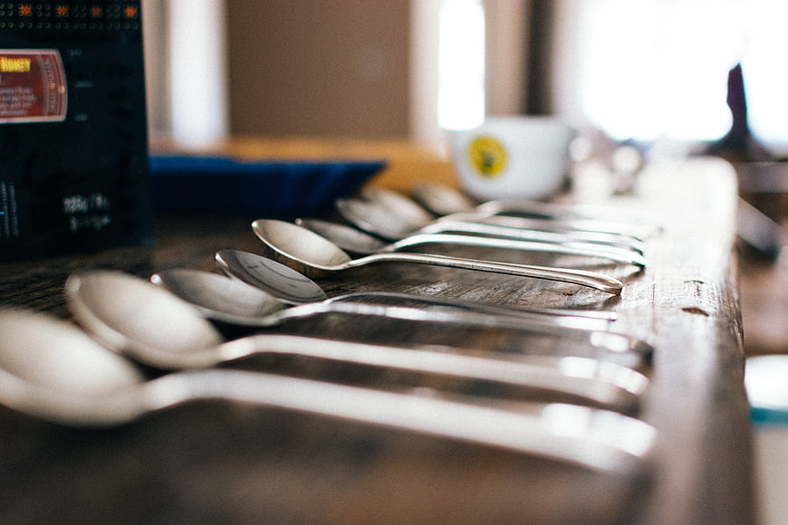 Row of silver spoons on rustic wooden table