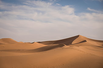 Golden Sand Dunes Under Blue Sky with Clouds