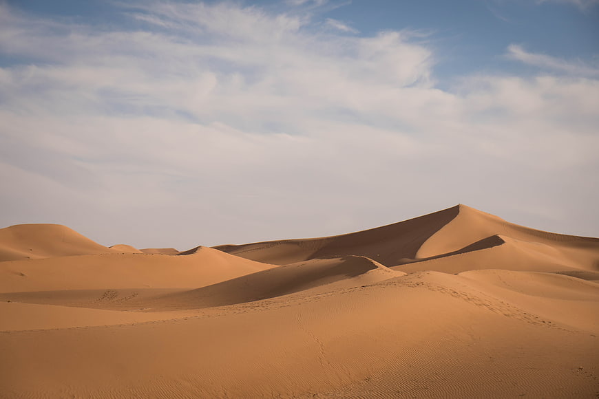 Golden Sand Dunes Under Blue Sky with Clouds