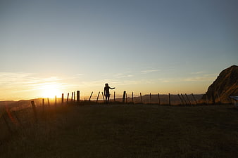 Silhouette of person standing on hill at sunset