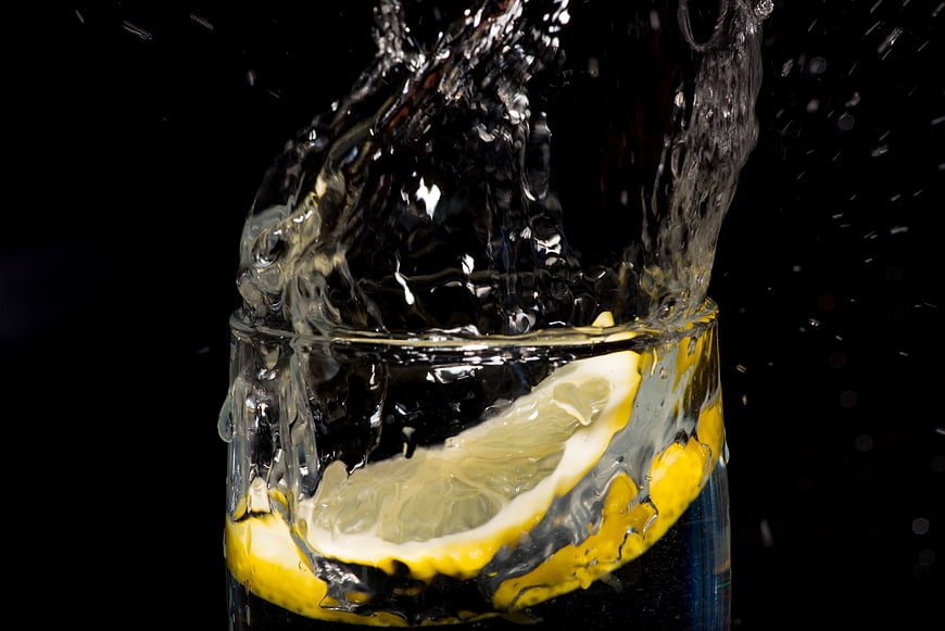 Refreshing lemon water splash in glass on black background