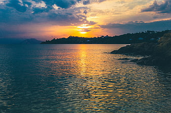 Golden Sunset Over Calm Ocean with Rocky Coastline