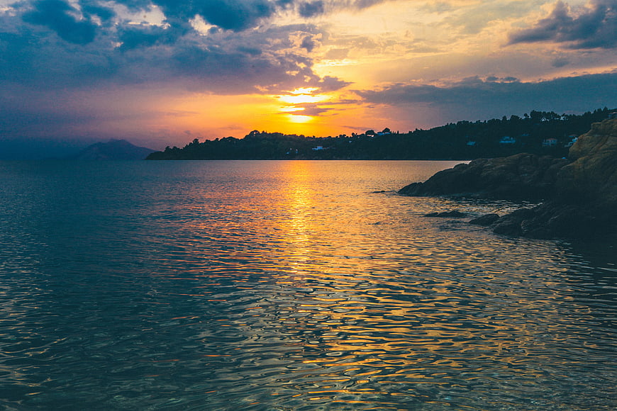 Golden Sunset Over Calm Ocean with Rocky Coastline