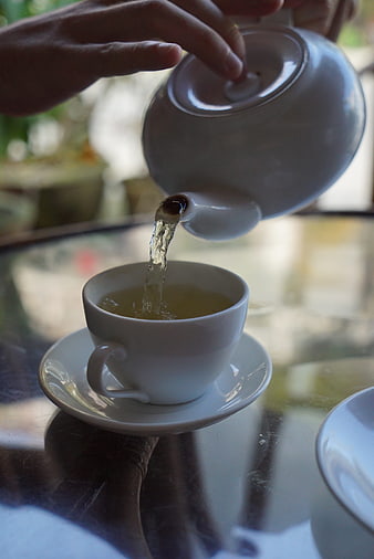 Pouring Hot Tea into White Cup on Glass Table
