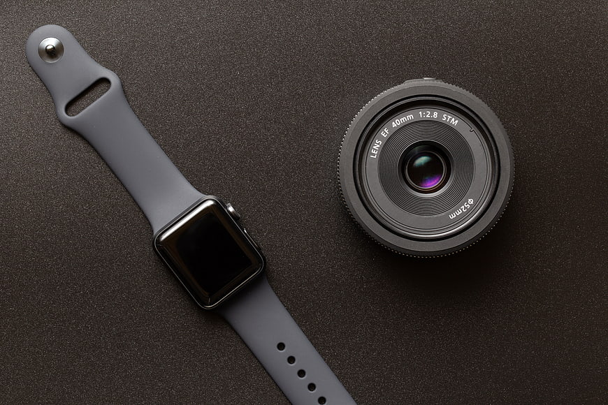 Smartwatch and Camera Lens Flat Lay on Dark Background