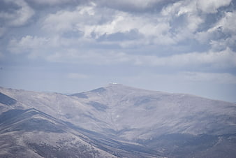 Snowy mountain peak with clouds and observatory