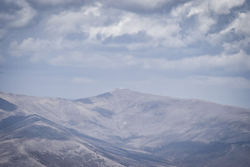 Snowy mountain peak with clouds and observatory