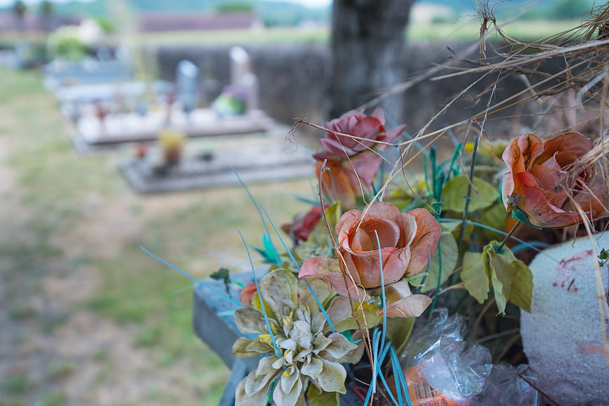 Wilted artificial flowers on a grave in a cemetery