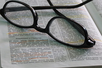 Black Glasses Resting on Open Bible Text