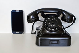 Vintage Black Rotary Telephone And Modern Smartphone On White Surface