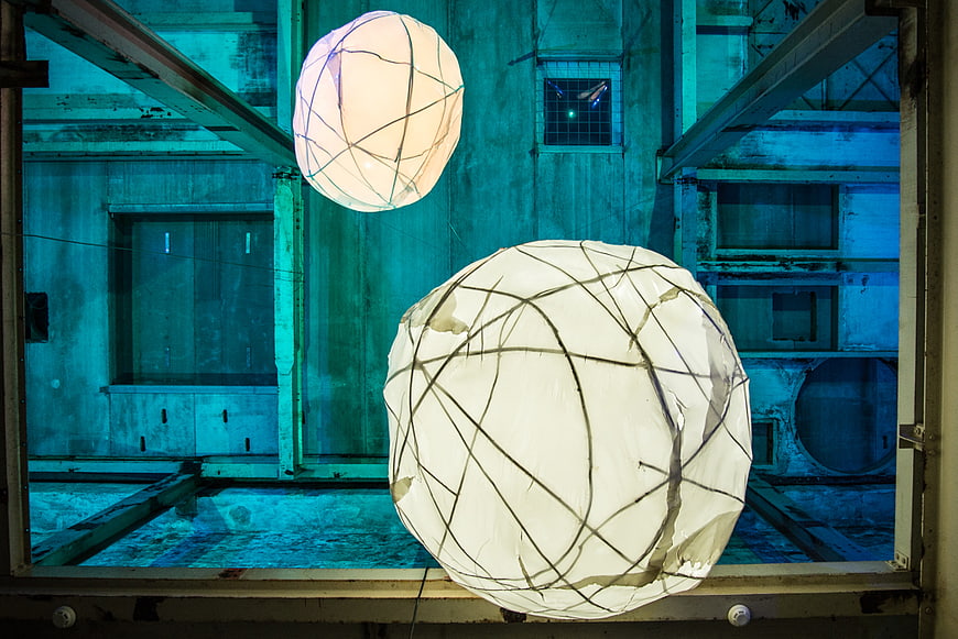 Glowing spherical lanterns in industrial blue warehouse interior