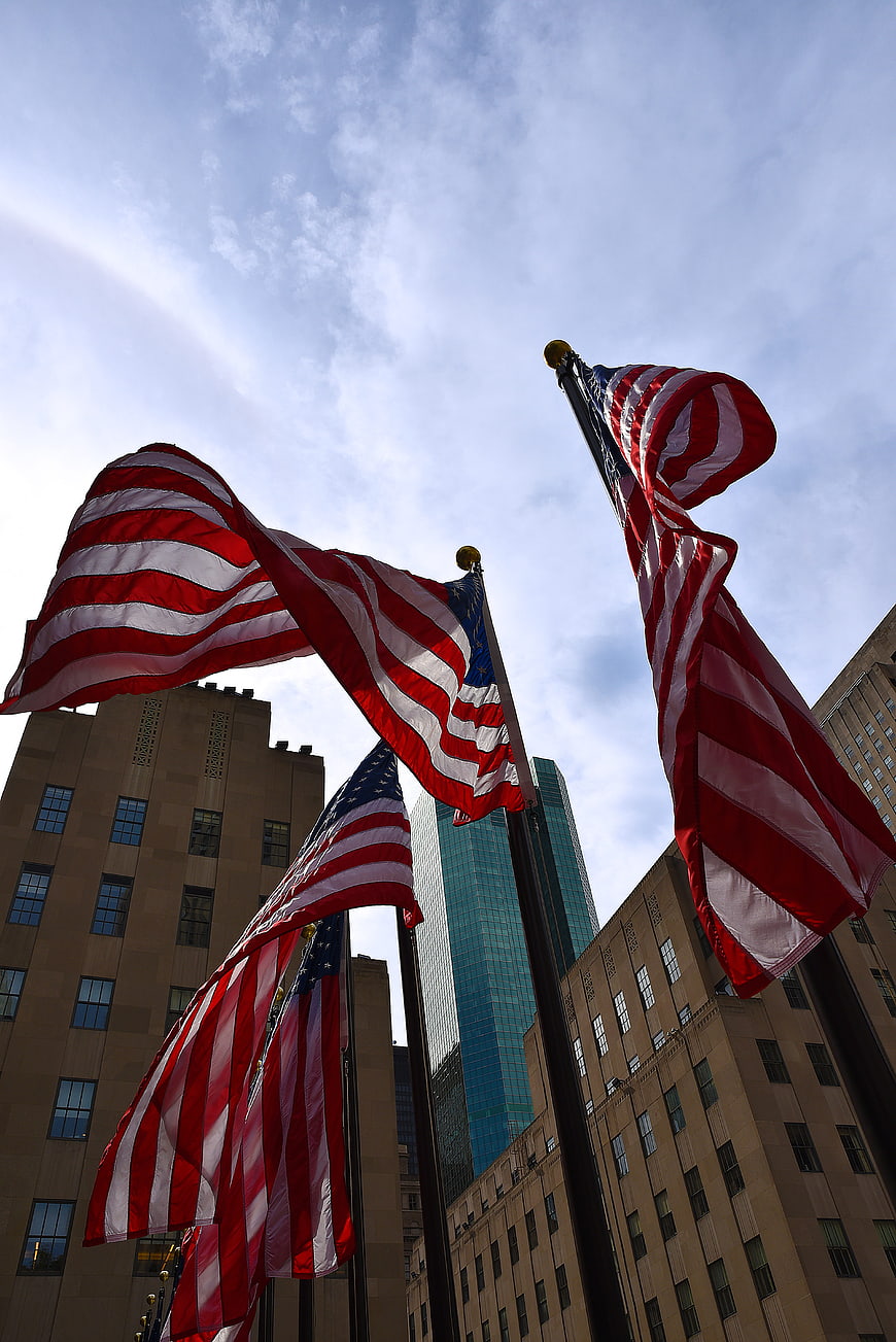 Low angle view of American flags waving in city