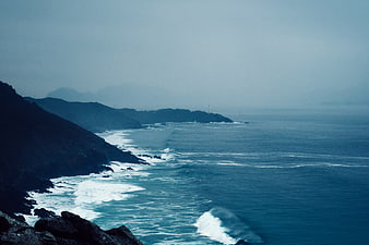 Misty Blue Coastal Landscape with Crashing Waves and Dark Cliffs