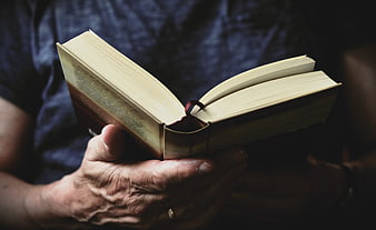 Senior Man Holding Open Book With Weathered Hands