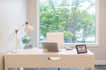 Modern white home office desk with laptop and window view
