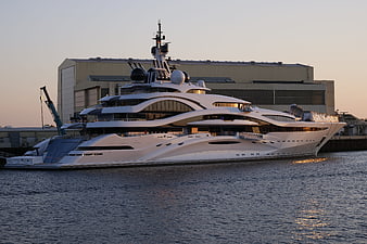Luxury white superyacht docked at shipyard at sunset