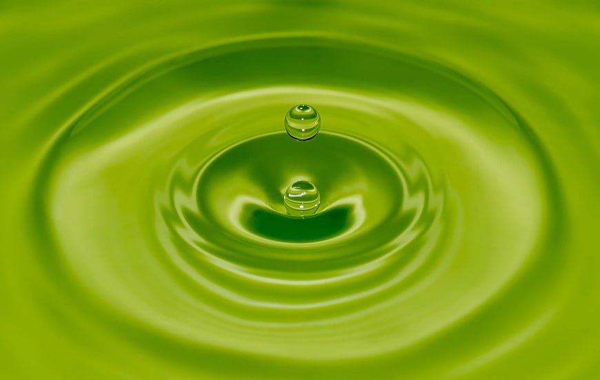 Green liquid splash with water droplets and ripples