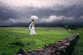 Wedding Couple Embracing Under White Umbrella In Irish Meadow