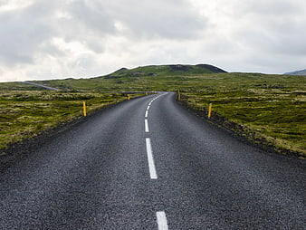 Empty asphalt road winding through green Icelandic landscape