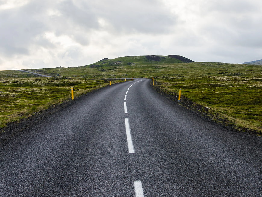 Empty asphalt road winding through green Icelandic landscape