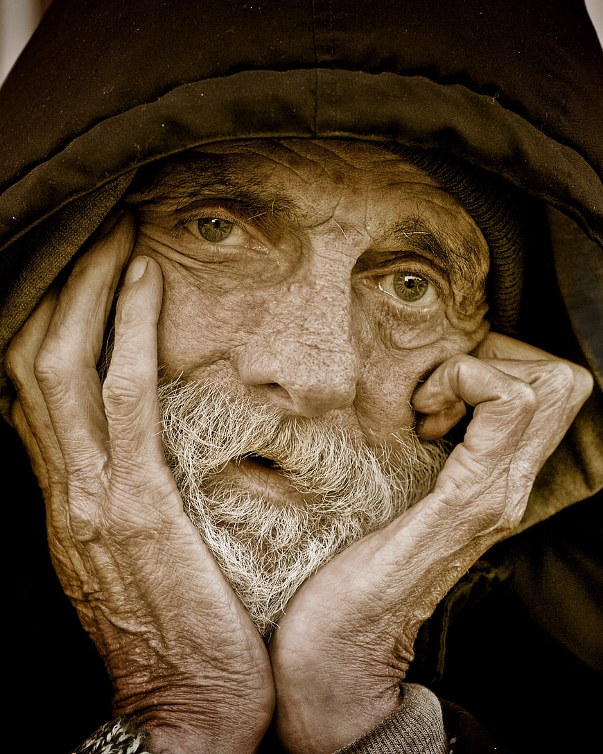 Close-up portrait of elderly homeless man with weathered face