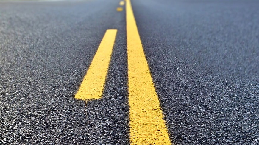Low angle view of yellow road lines on blue asphalt