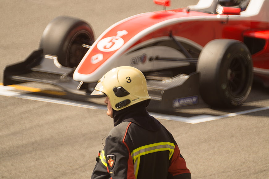Race track marshal watching red formula one car pass