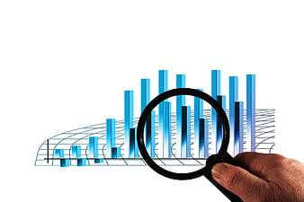 Hand holding magnifying glass over blue 3D bar chart