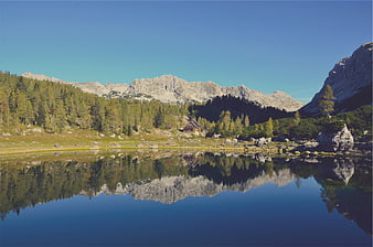 Serene Alpine Lake with Mountain Reflection and Wooden Cabin