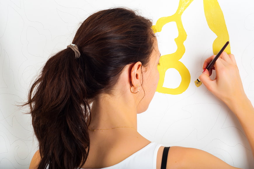 Woman Painting Yellow Wall Design With Brush