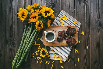 Flat lay of sunflowers, coffee, and brownies on rustic wood