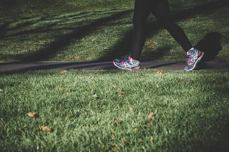 Runner's legs and colorful sneakers on a park path